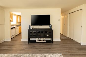 A black TV stand with the word HOME on it sits in a living room at Hyde Park Apartments*, Essex, MD 21221
